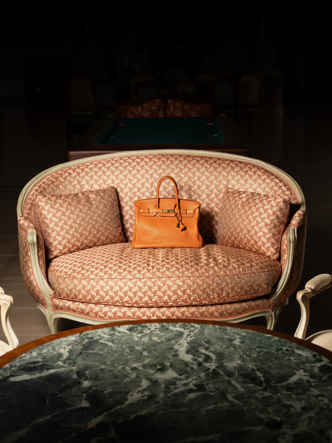 Hermès Birkin bag in brown leather on an upholstered sofa in an elegant interior